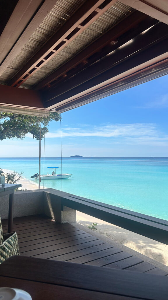 Beachfront view with turquoise water and a boat. For a horizontal crop, preserve the boat and water